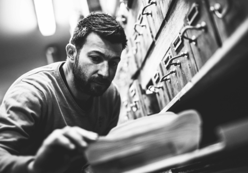Photo en noir et blanc de l'artiste Antoine Dufilho regarde l'une de ses œuvres.